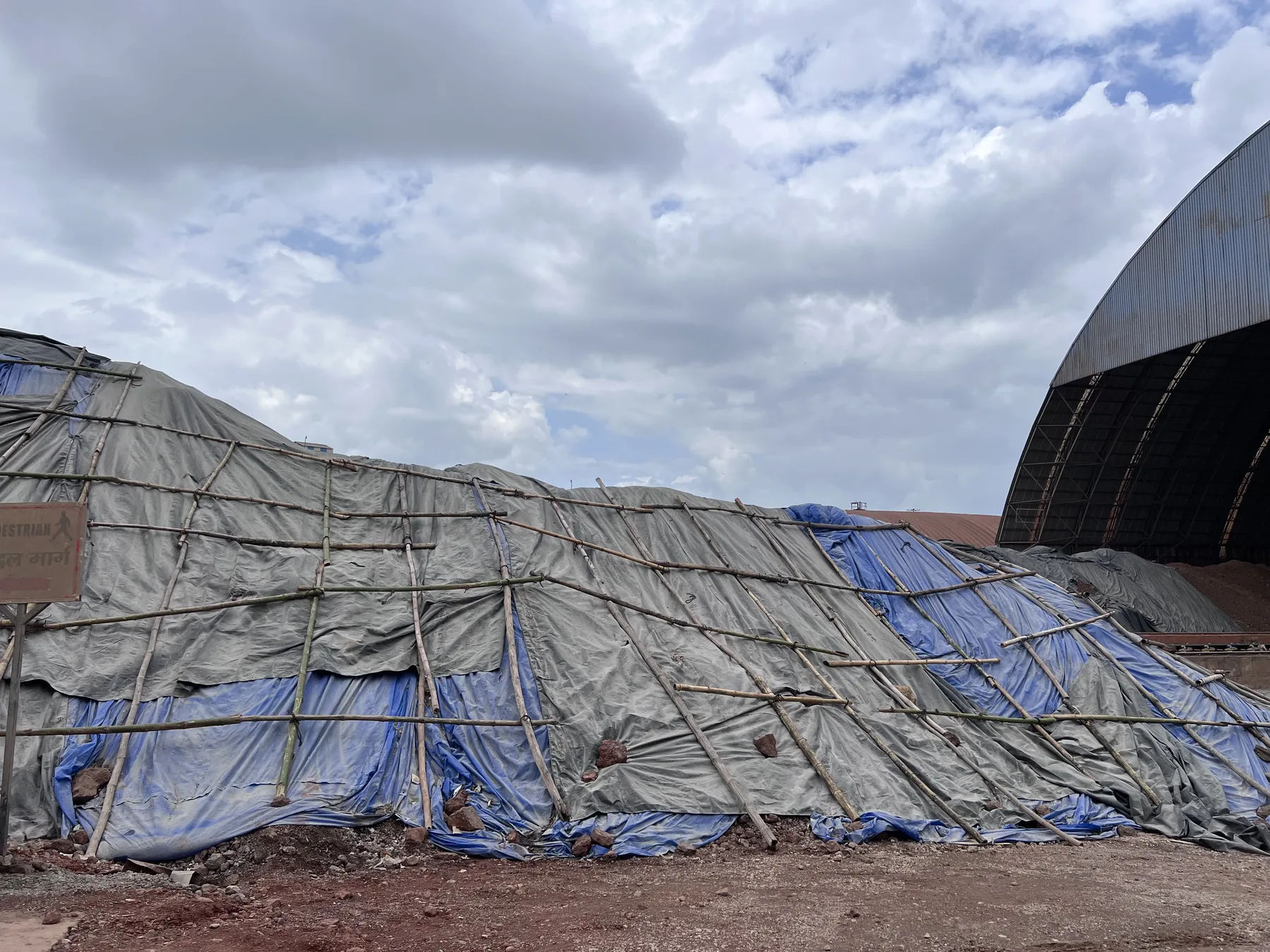 Bamboo-Framed Tarpaulin Covering a Raw Material Stockpile at a Plant
